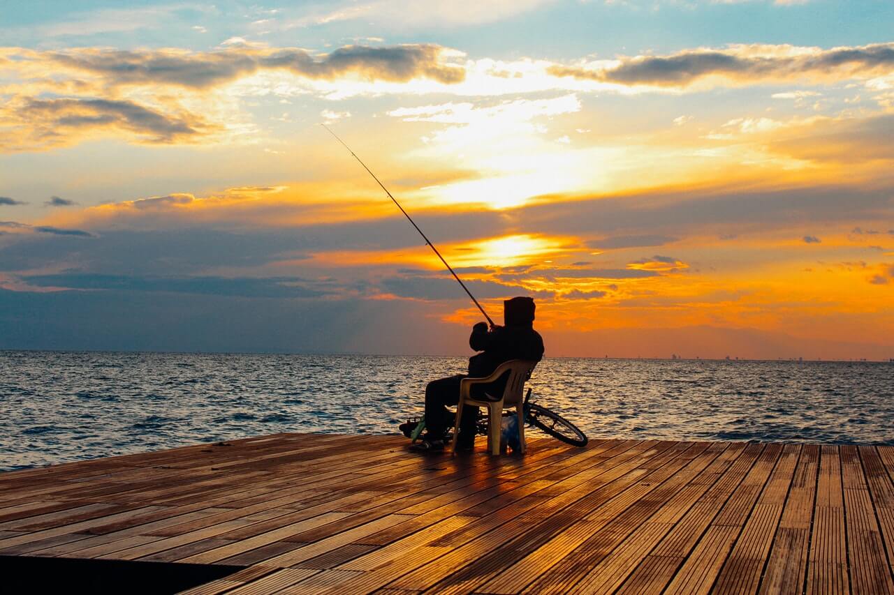 person sitting on chair holding fishing rod