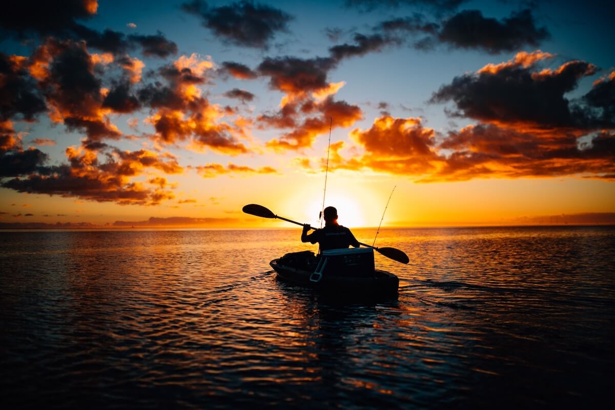 man kayak fishing in sunset